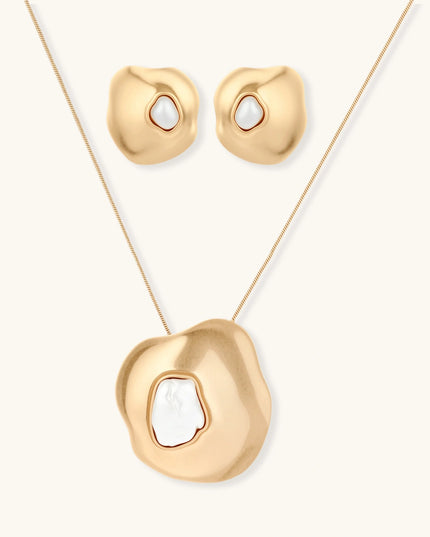Schmuckset in mattem Gold mit organisch geformtem Anhänger und Ohrringen, jeweils mit weißer Barockperle